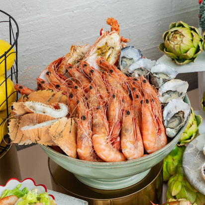 Assorted seafood including prawns, oysters, and lobster tails on a table.