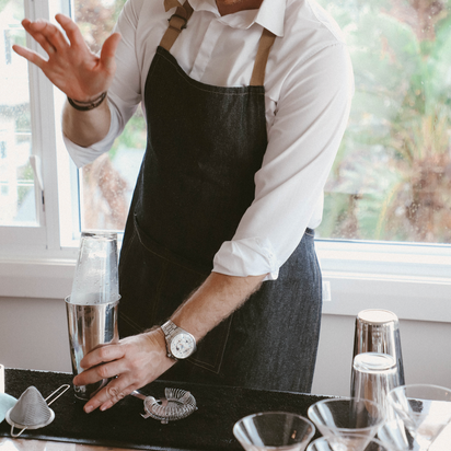 Man in a chef's apron preparing COCKTAILS