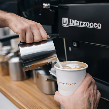 Barista pouring a latte into a Pomelo & Co cup at a coffee cart