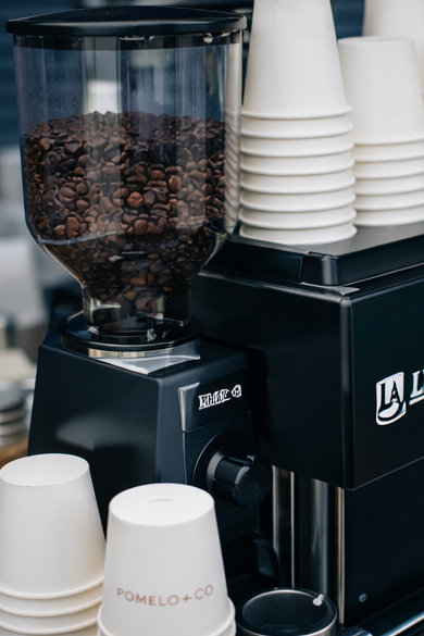 Coffee grinder, espresso machine and Pomelo & Co cups on a coffee cart