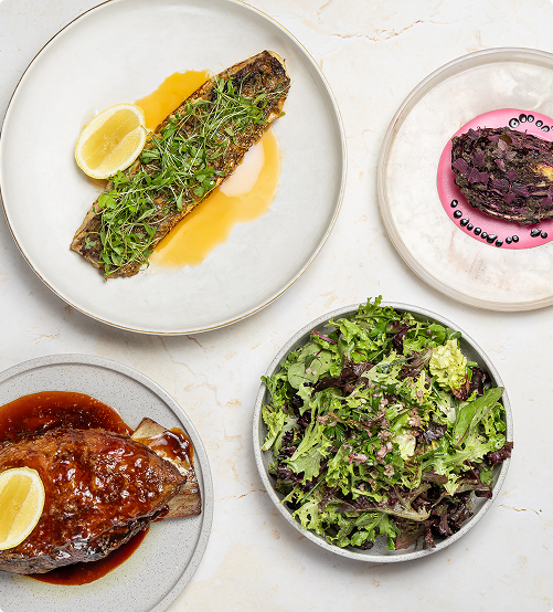 Various dishes including lamb shank, salmon, salad and cabbage.